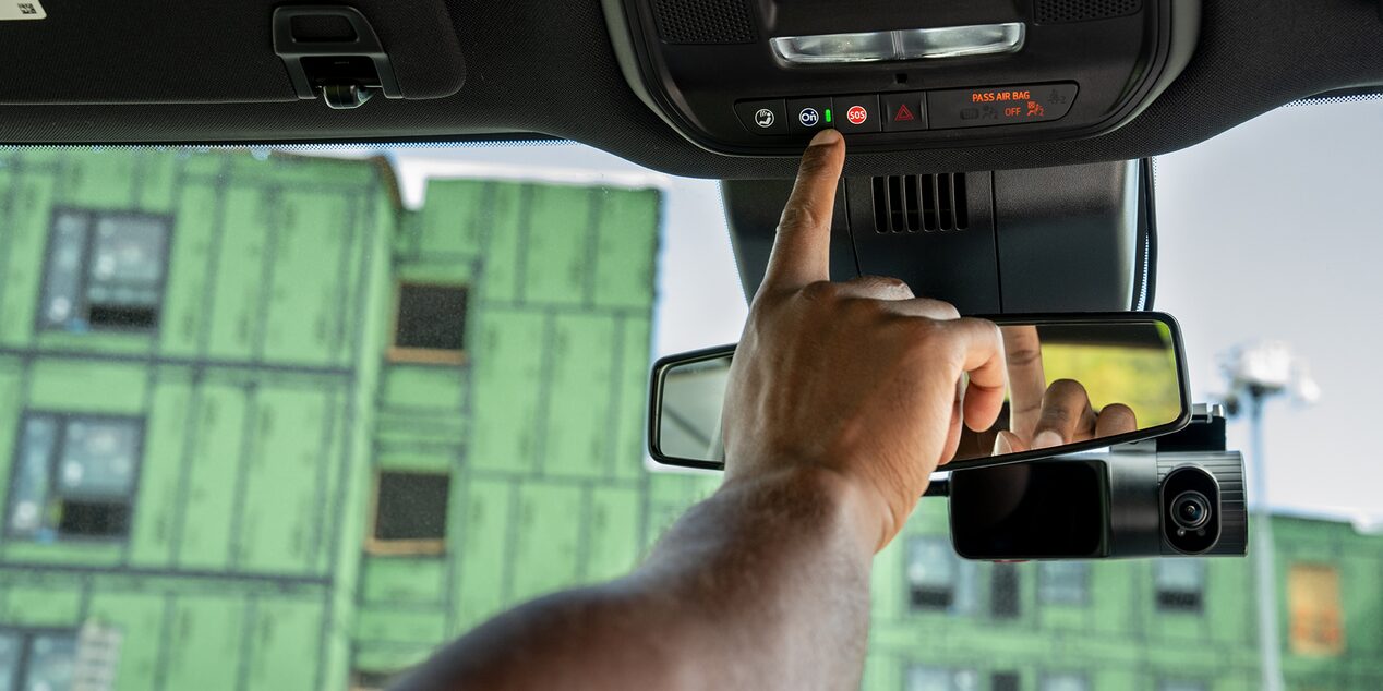 A construction worker pressing the OnStar button in their Silverado.