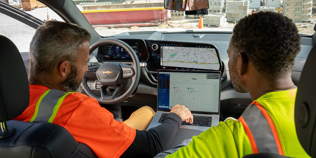 Two construction workers sitting in a Chevrolet SIlverado accessing telematics data on a laptop.