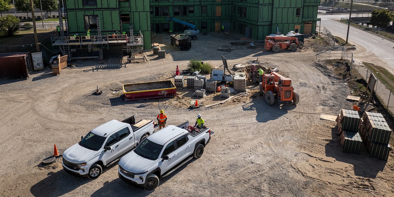 Two White Chevrolet Silverados parked on a construction site, viewed from above.