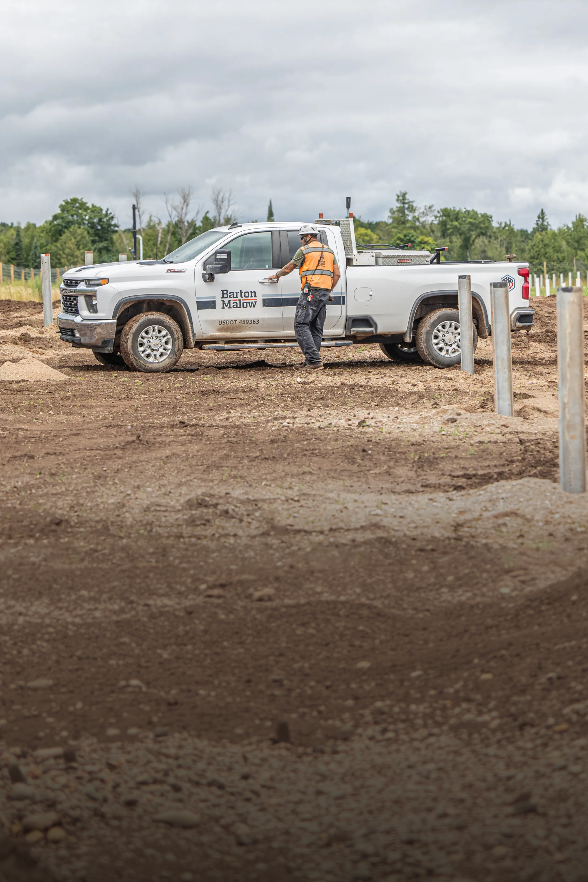 A custruction worker walking to their Barton Mallow branded Chevrolet Silverado