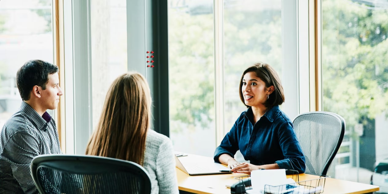 A Couple Talking to a Lady Sitting at a Desk