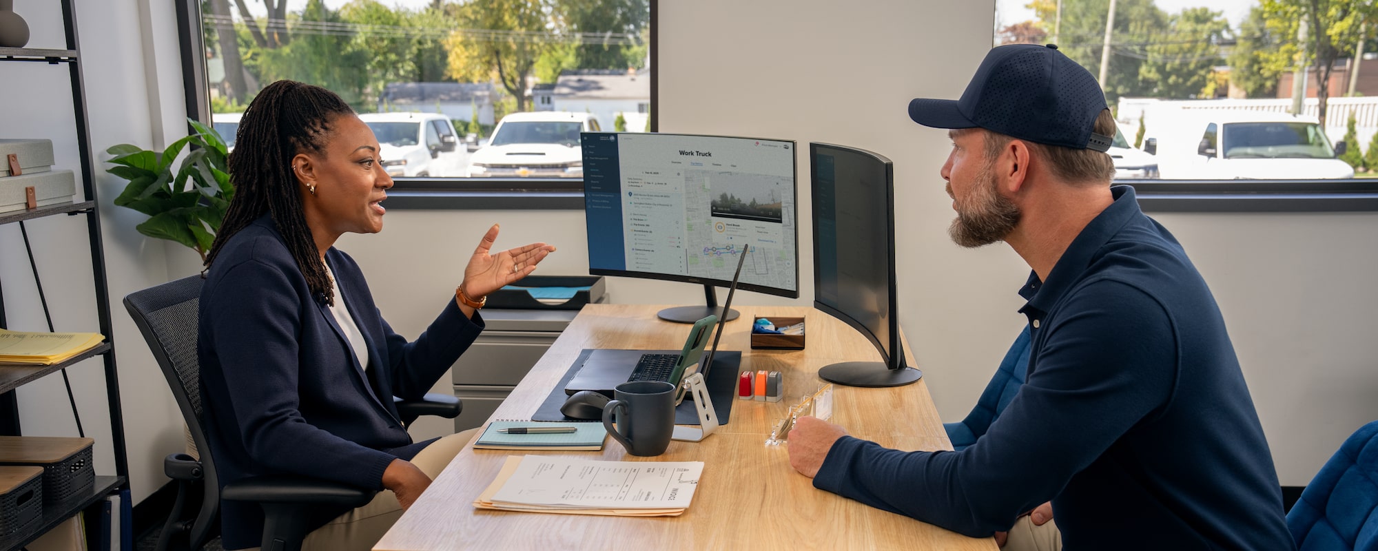 Two people speaking across a desk in an office