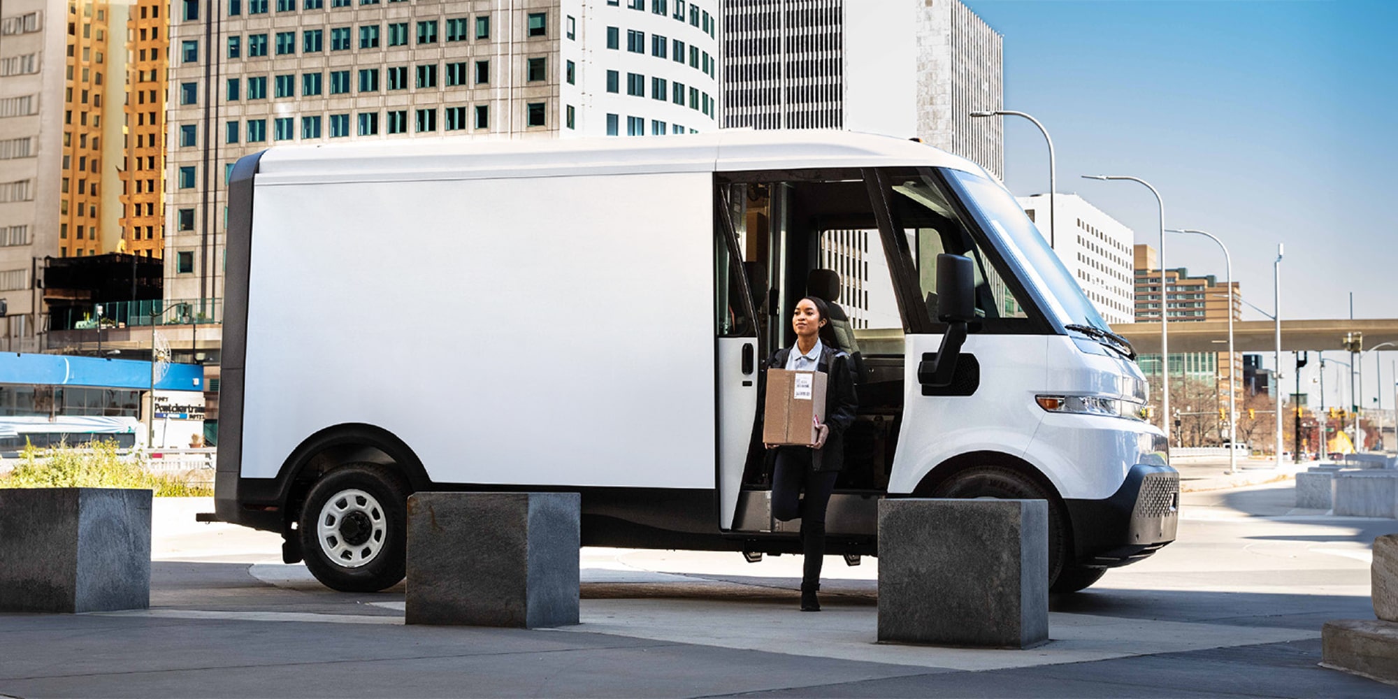 A delivery driver carrying a box out of a Chevrolet Brightdrop