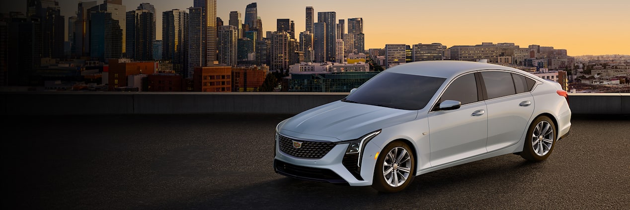 A Cadillac sedan in three-quarters view in front of a city skyline