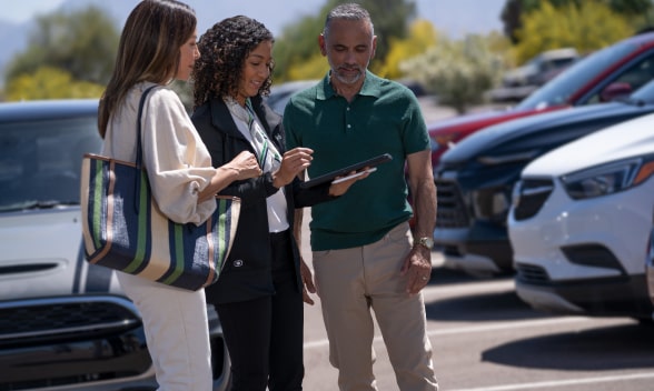 A GM car dealer helping two customers find their next vehicle