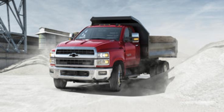 three-quarter front view of a Chevrolet dump truck on a job site.