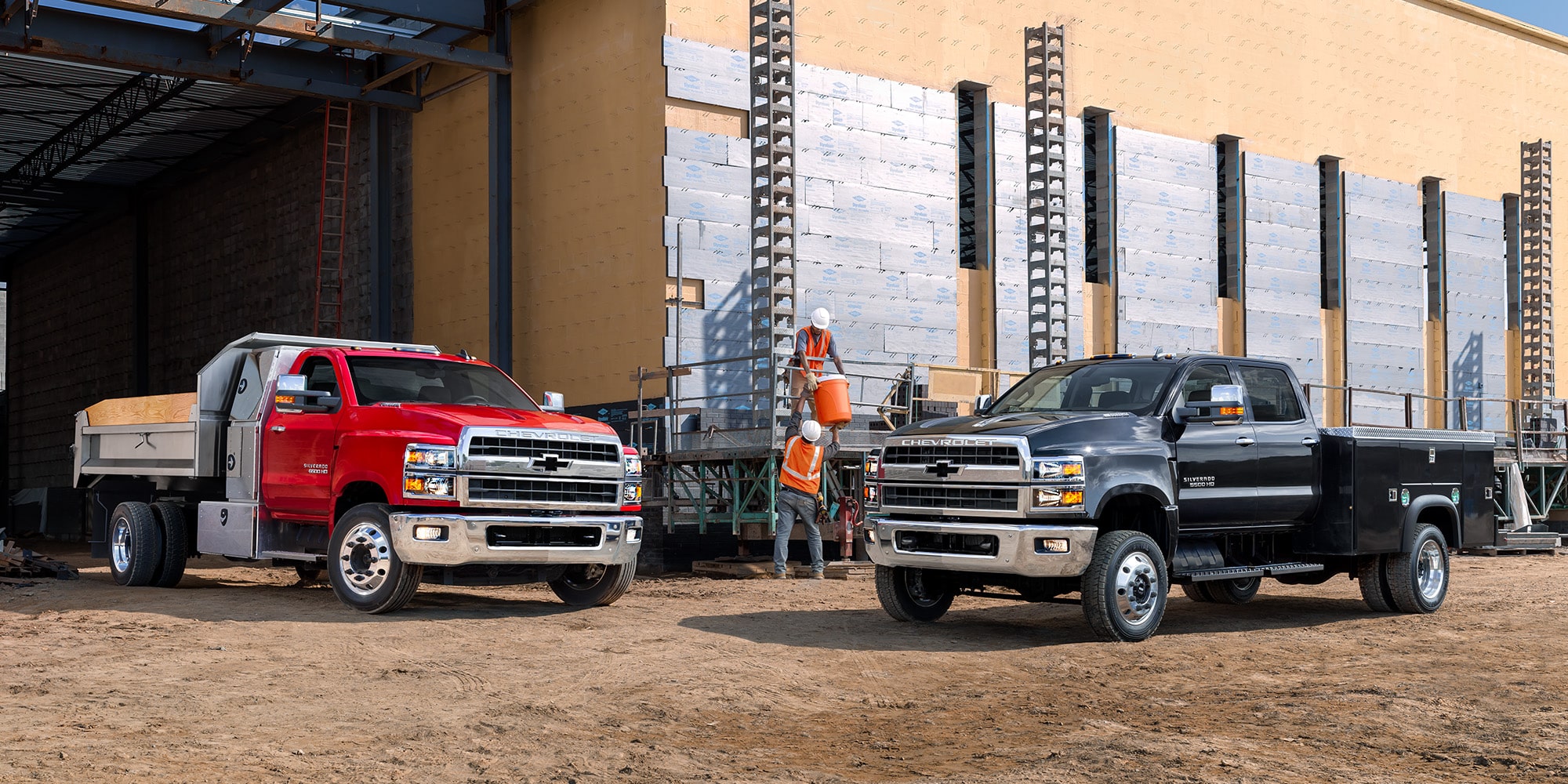 Two upfit Chevrolet trucks parked on a jobsite