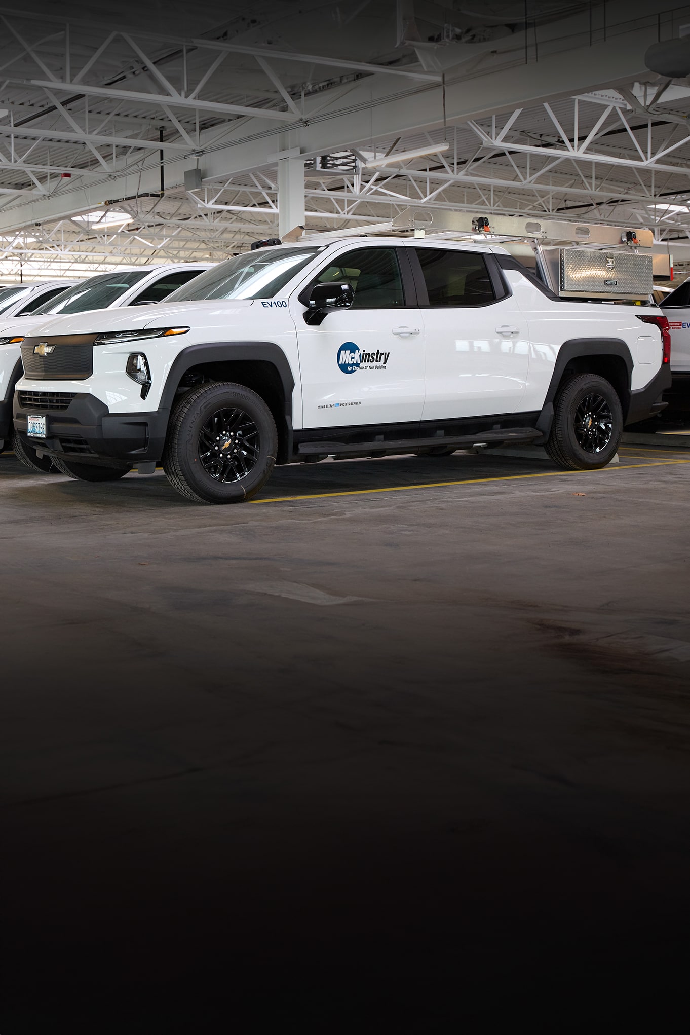 A white Chevrolet Silverado EV with a McKinstry logo on the door parked in a garage