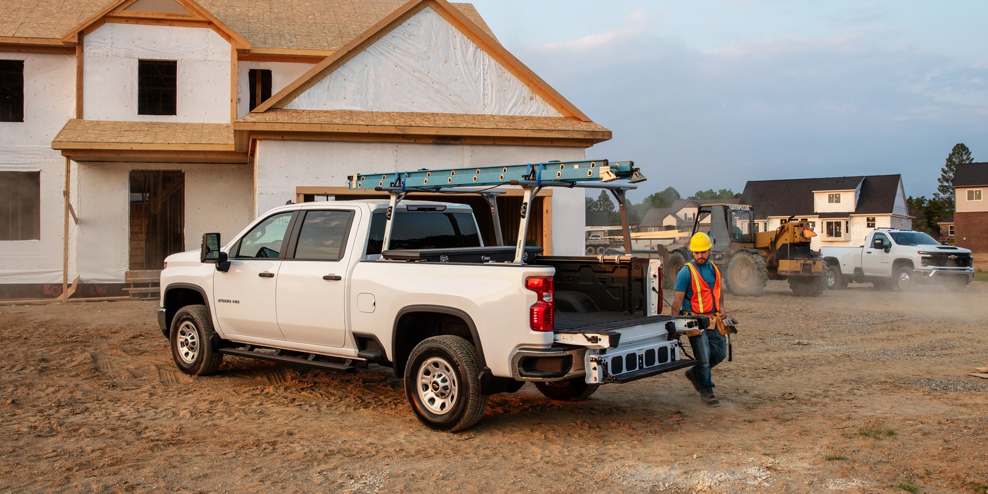 A construction worker walking up to the tailgate of a Silverado HD.