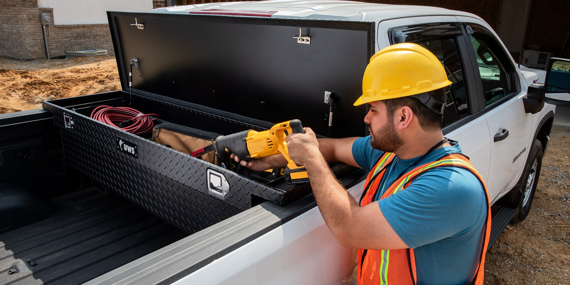 A construction worker removing tools from the tool box of a Silverado HD