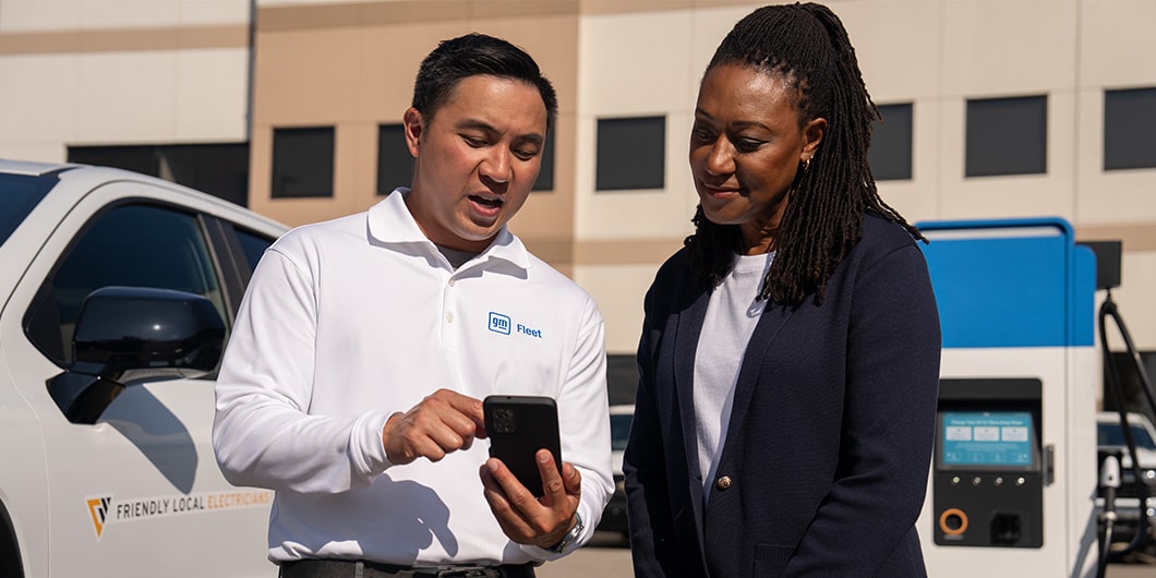 A GM EV Expert talking with a customer at an EV charging station.