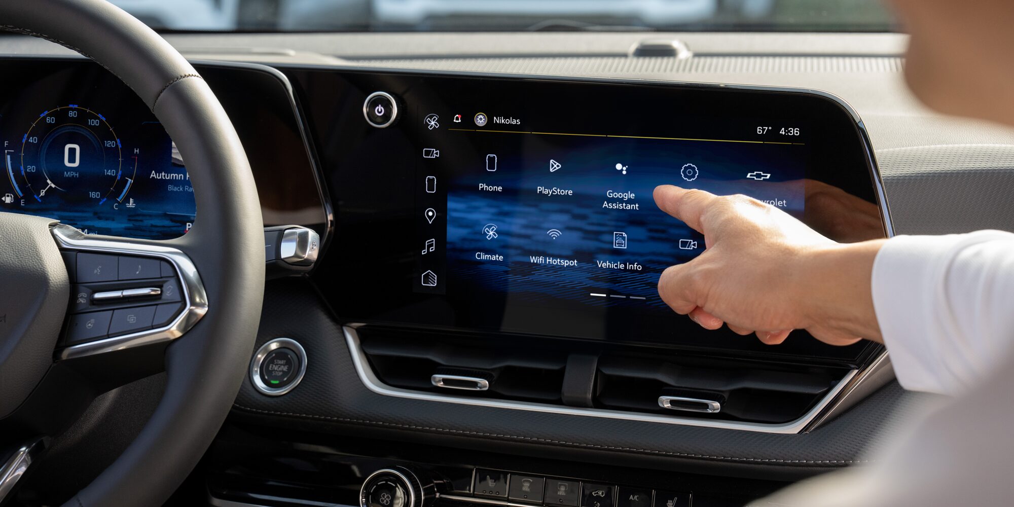 A passanger pointing at the Chevrolet Equinox infotainment system. 