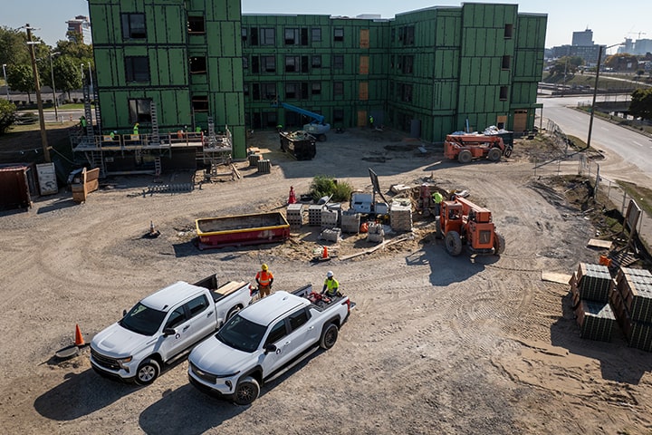 A skyview of a construction site with two Chevrolet Silverados parked.