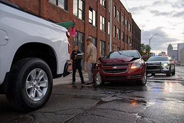 Two workers talking near the tailgate of a Chevrolet Silverado