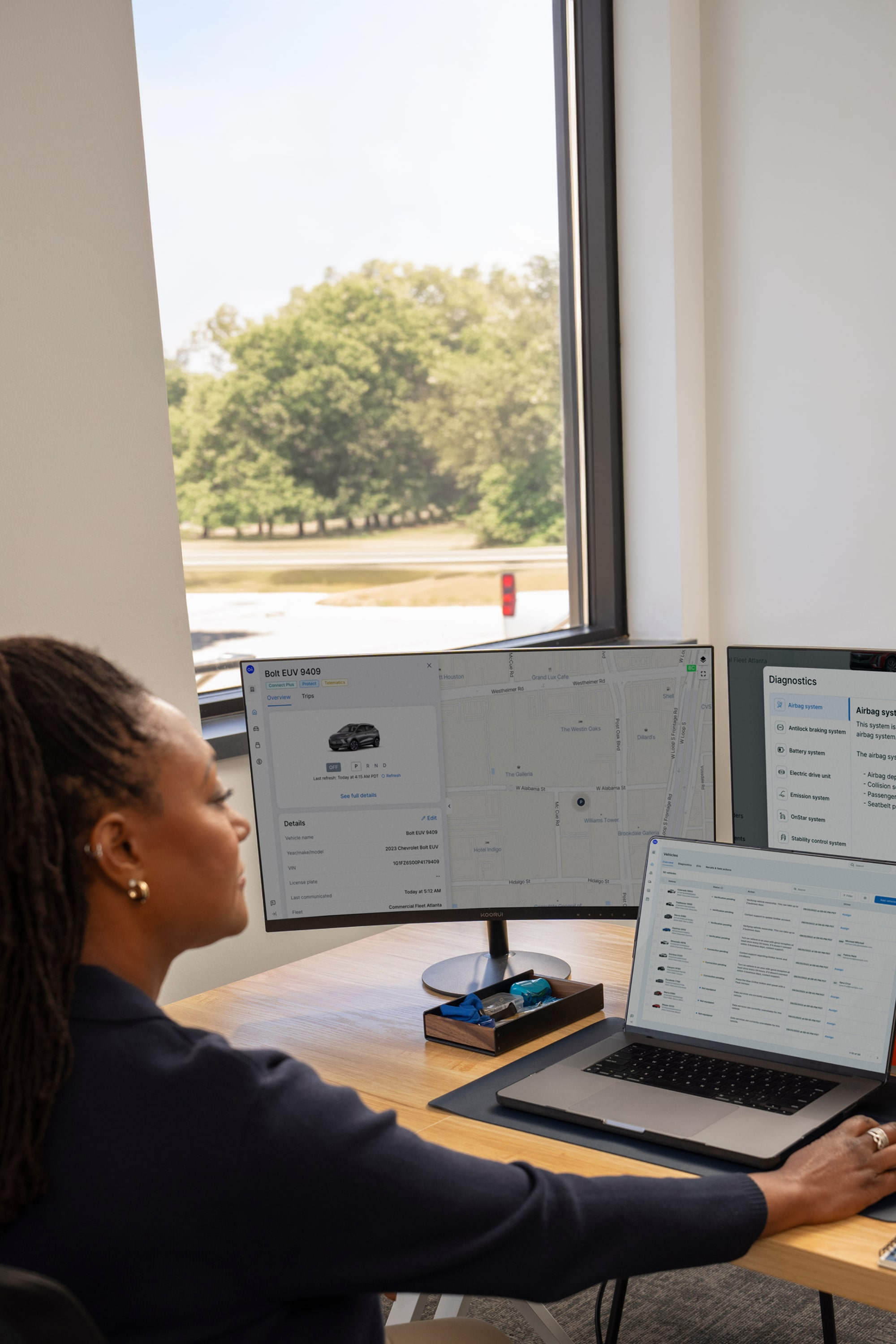Fleet telematics open on two monitors and a laptop screen.