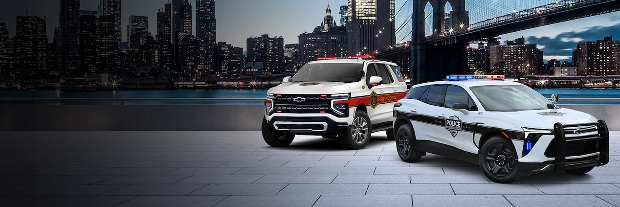 A GM Fleet Police Vehicle parked with a GM Fire Vehicle infront of a skyline