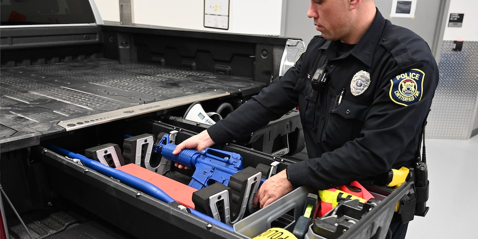 A police officer removing a weapon from teh built in equipment storage of a Chevrolet PPV 