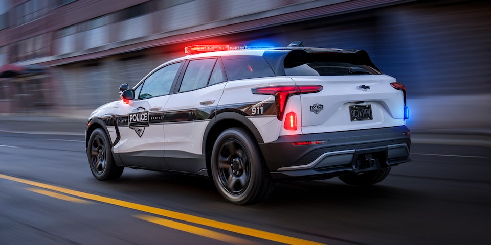 A Chevrolet Blazer PPV driving down a road with it's emergency lights on