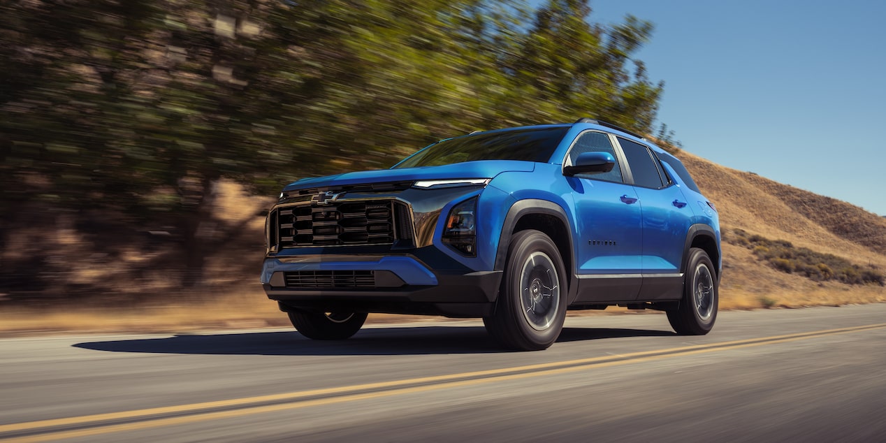 A blue 2027 Chevrolet Equinox driving down a road.