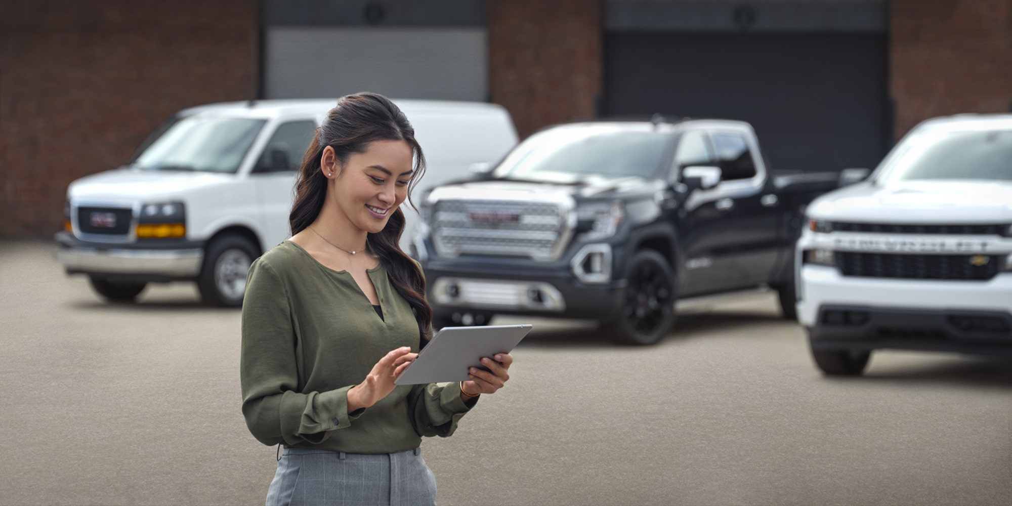 A worker using a tablet in front of a fleet of GM Fleet Trucks