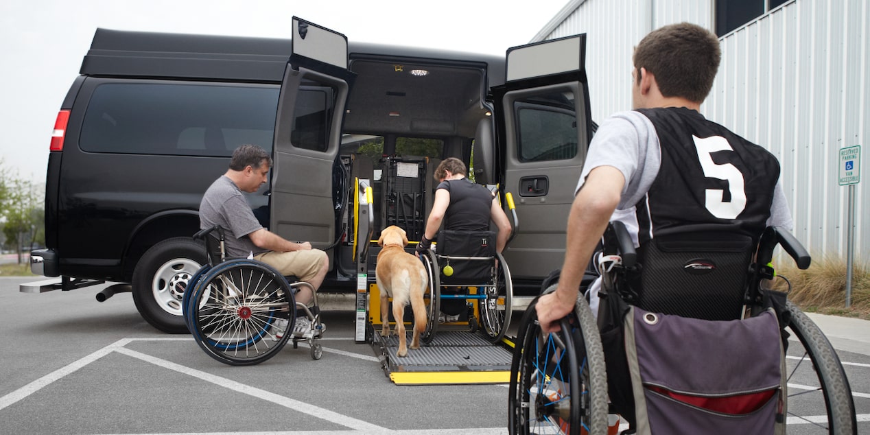 Three people in wheelchairs and their dog using the upfit wheelchair lift application.