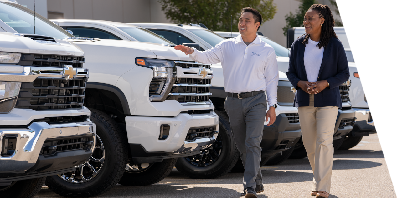 A GM Fleet sales associate showing a lineup of Chevrolet Silverados to a customer