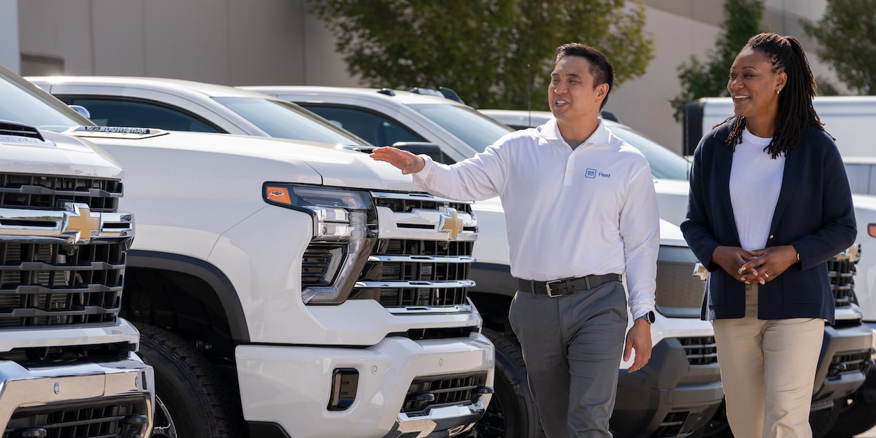 A GM Fleet sales associate showing a lineup of Chevrolet Silverados to a customer
