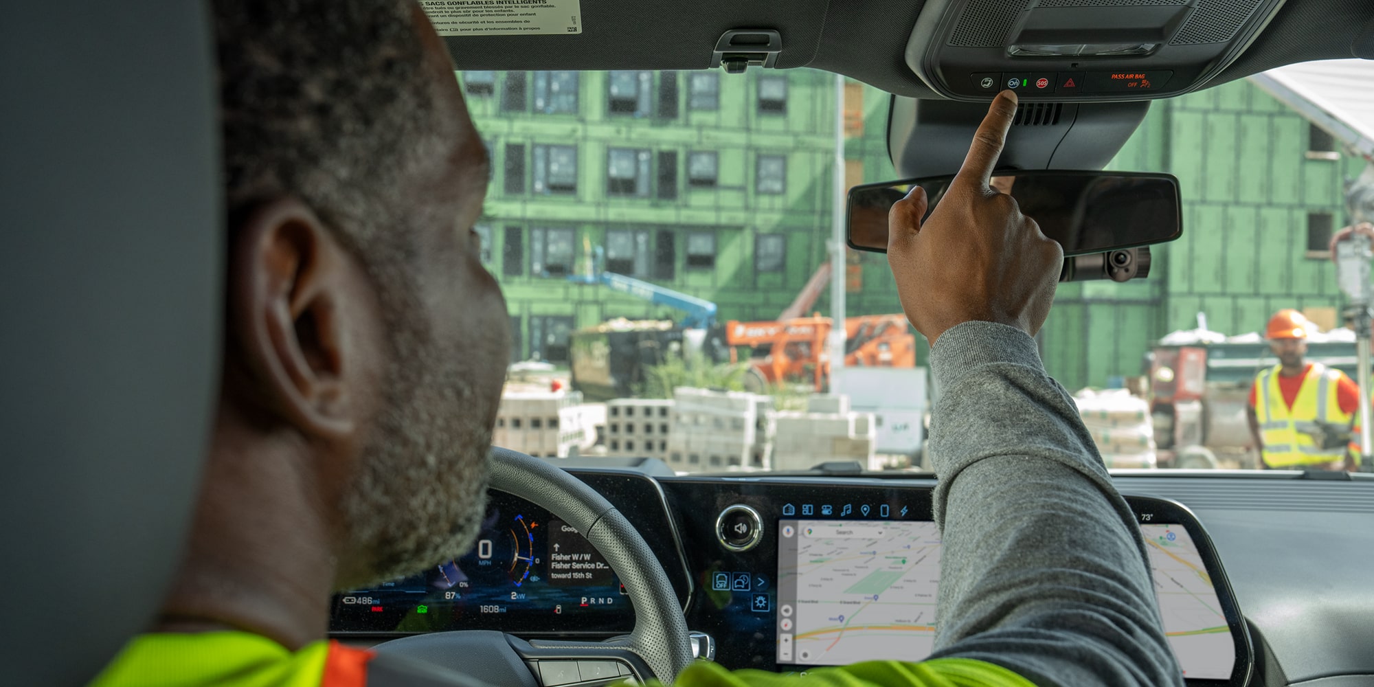 A construction worker pressing the OnStar button inside their Chevrolet Silverado.