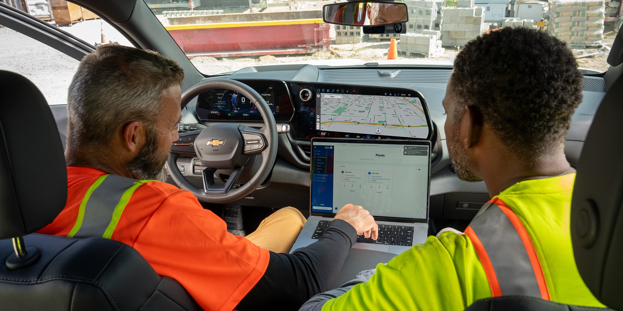 Two construction workers sitting inside the Chevrolet Silverado, accessing OnStar Vehichle Insights from a laptop.