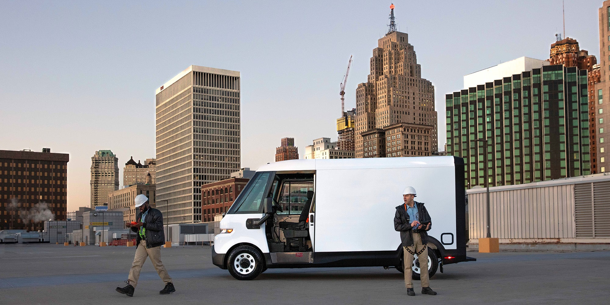 A white Chevrolet BrightDrop parked, as two workers walk away.