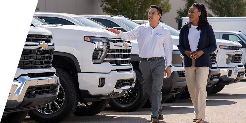 A GM Fleet sales associate showing a lineup of Chevrolet Silverados to a customer