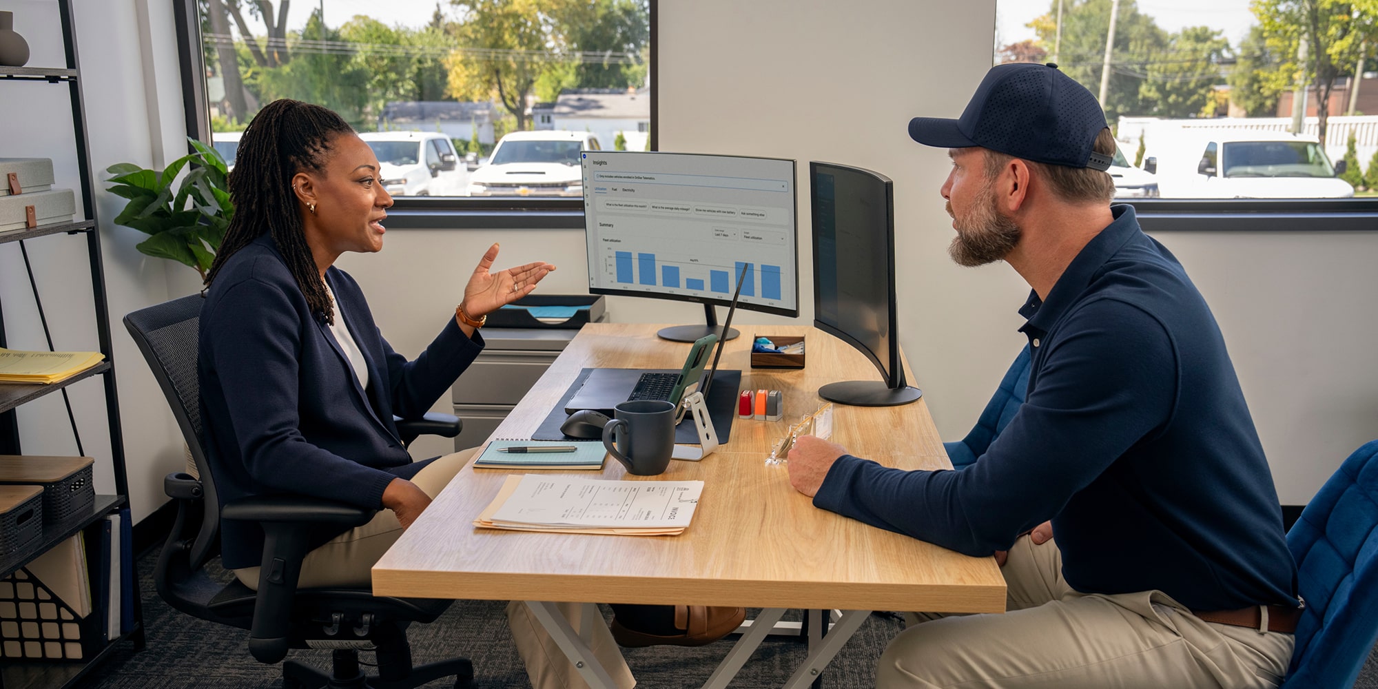 A GM Fleet specialist talking to a customer at their desk.