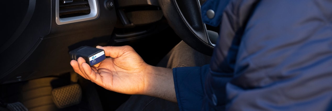 A closeup of someone plugging in an OnStar Fleet Adapter