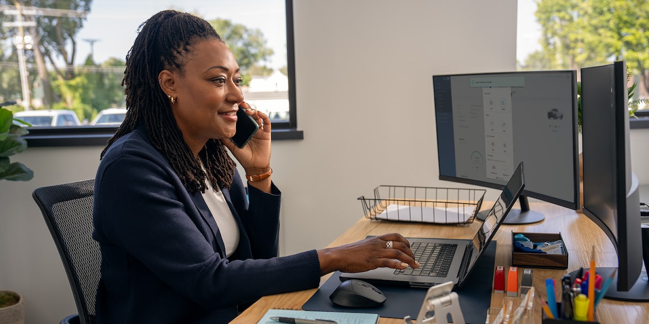 An office worker on the phone while examining vehicle information on their monitors