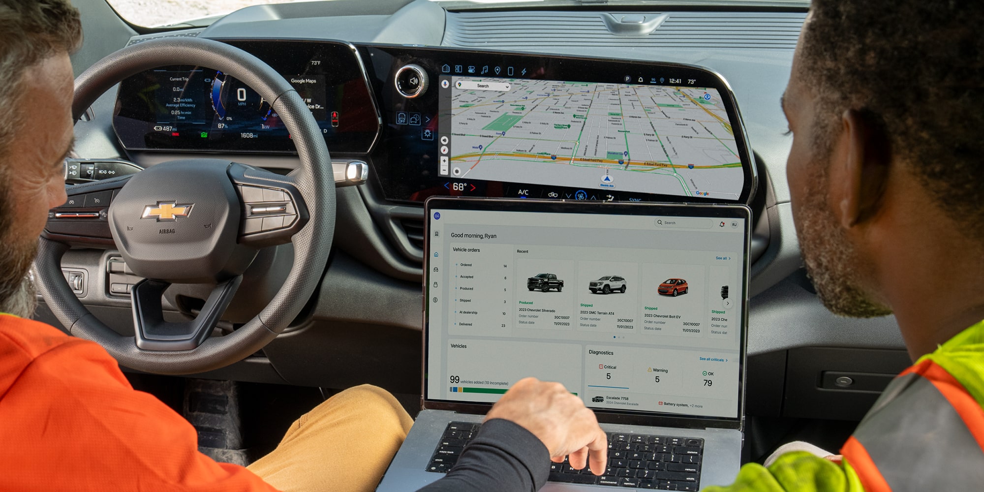 Two workers using a laptop and the infotainment system in their Chevrolet Silverado. 