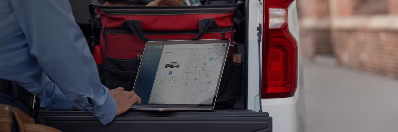 Someone Accesing OnStar Vehicle Insights from a laptop on their truck's tailgate.