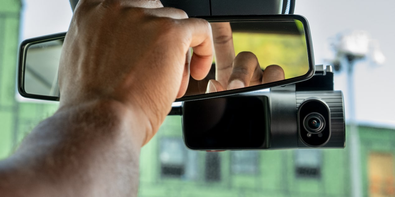 A close up of someone pushing the OnStar button in their vehicle. 