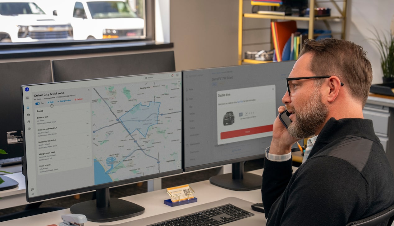 An office worker talking on the phone with telematics on his laptop screen.