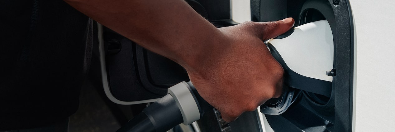 A hand plugging an ev charger into their GM Fleet vehicle