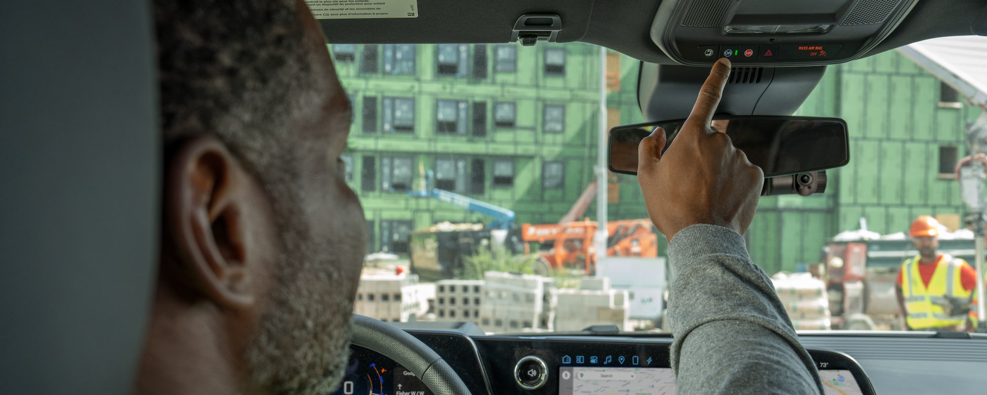 A driver pressing the OnStar button in their GM vehicle.