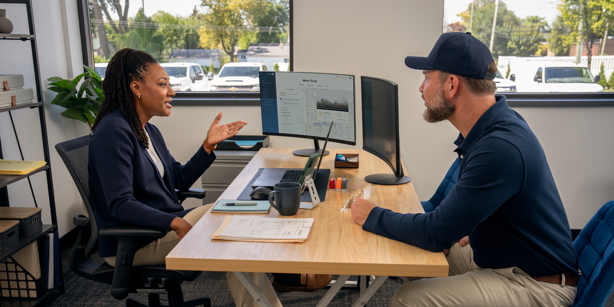 A GM Fleet specialist talking to a customer at their desk.