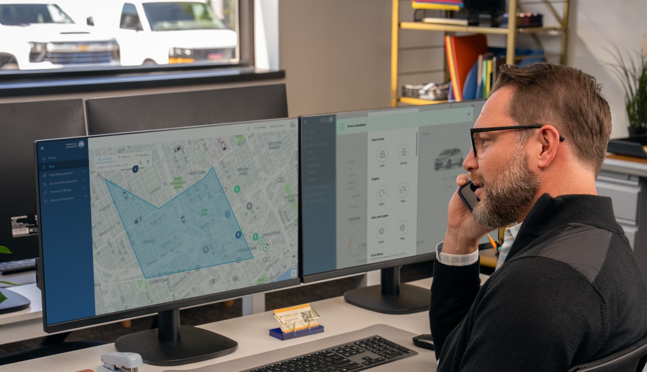 An office worker talking on the phone with telematics on his laptop screen.