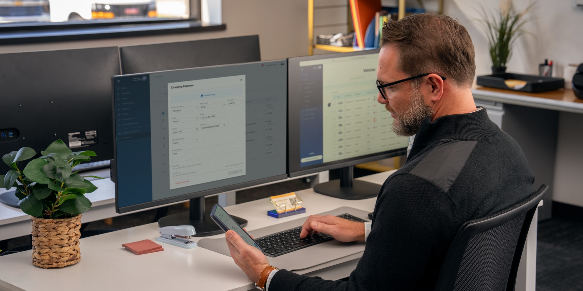 An office worker using GM Fleet telematics on his phone and computer.