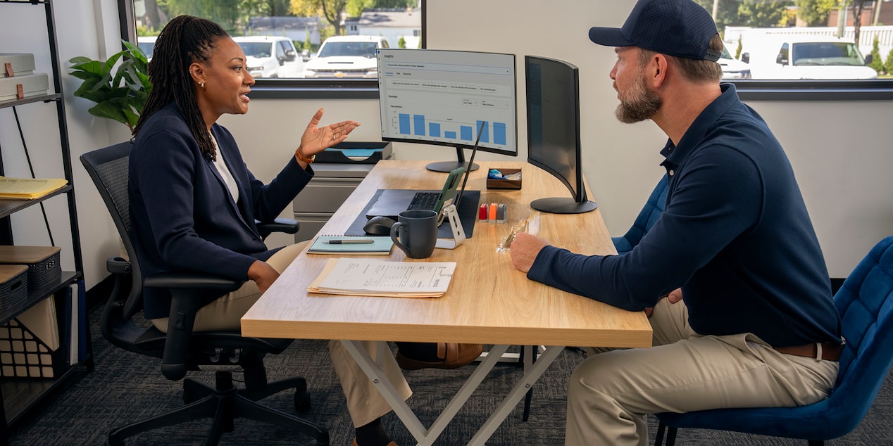 Two office workers speaking across a desk