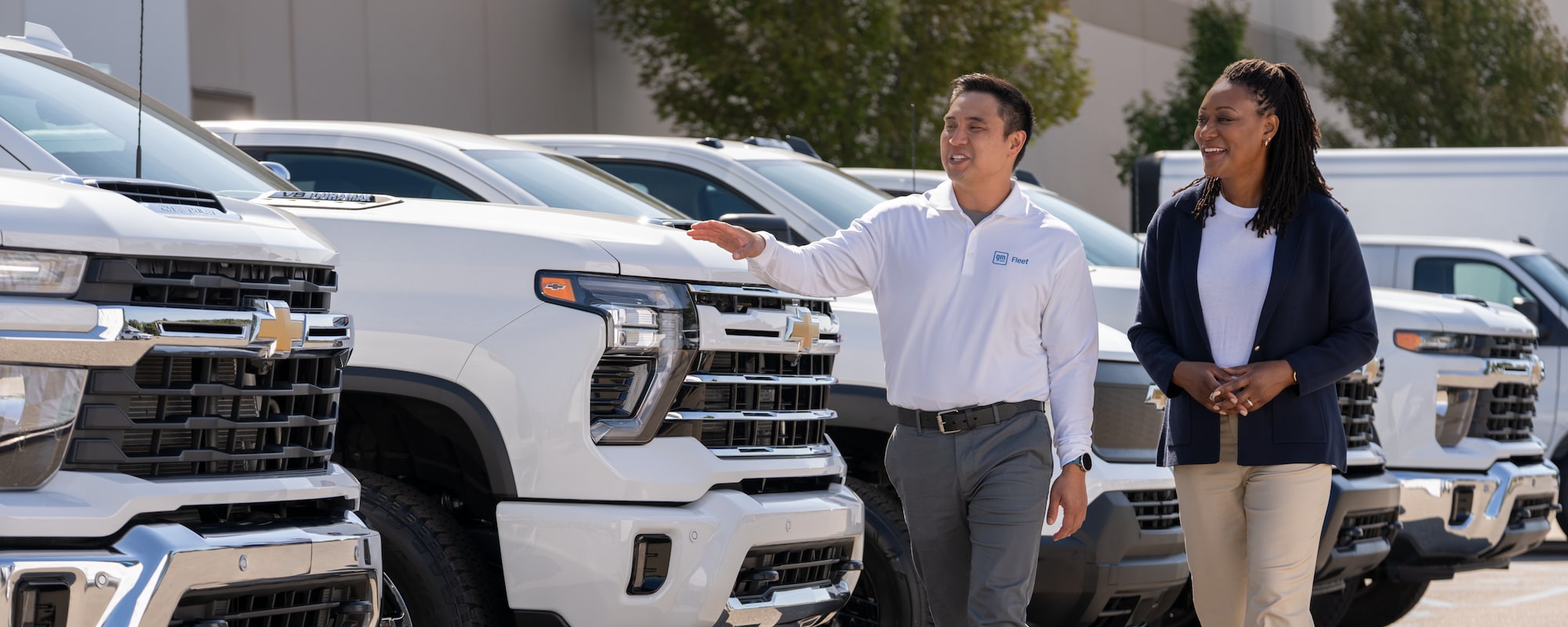 A GM Fleet specialist showing a customer a lineup of Chevrolet Silverados
