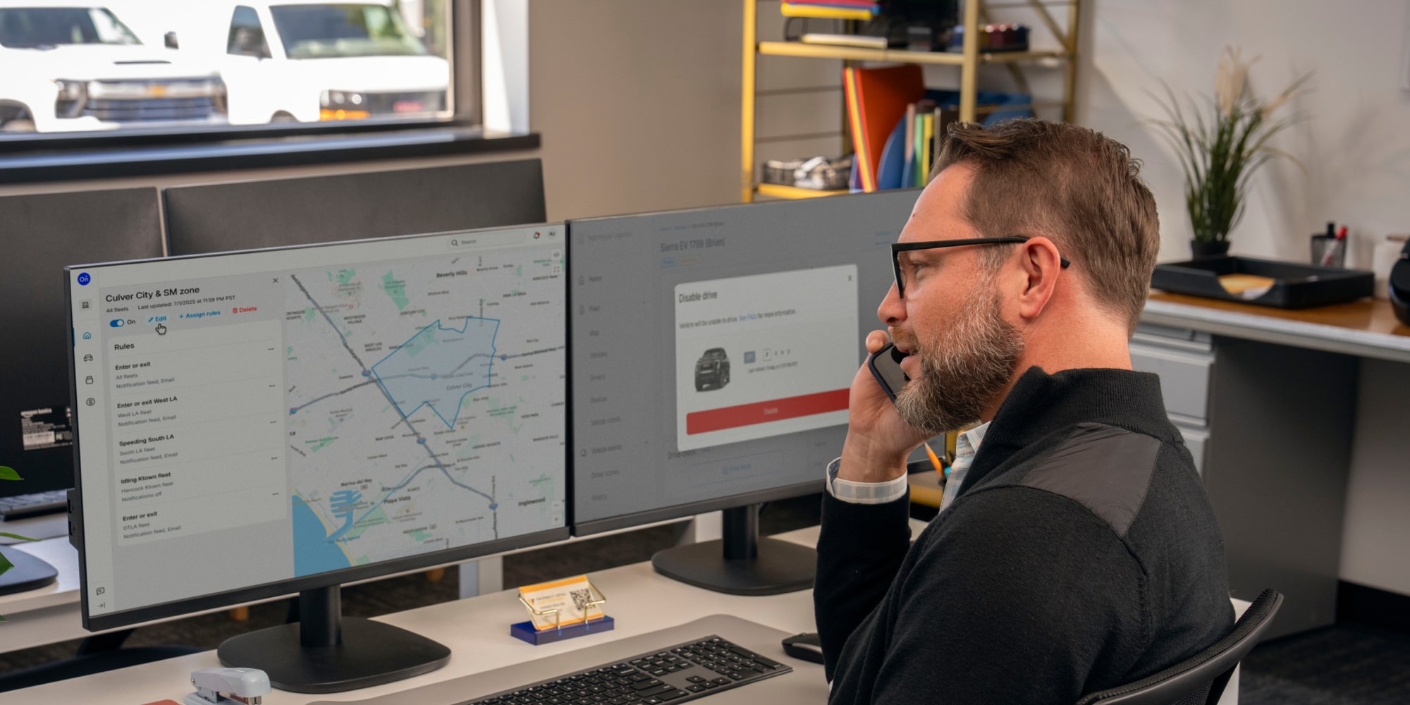An office worker talking on the phone with telematics on his laptop screen. 