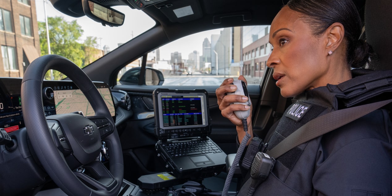 A police officer speaking on their radio in their Chevrolet PPV.