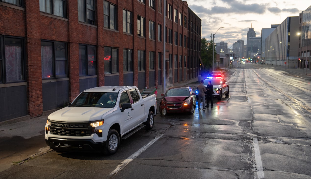 Two GM Vehicles that have been involved in a crash while a cop parks with it's lights on.