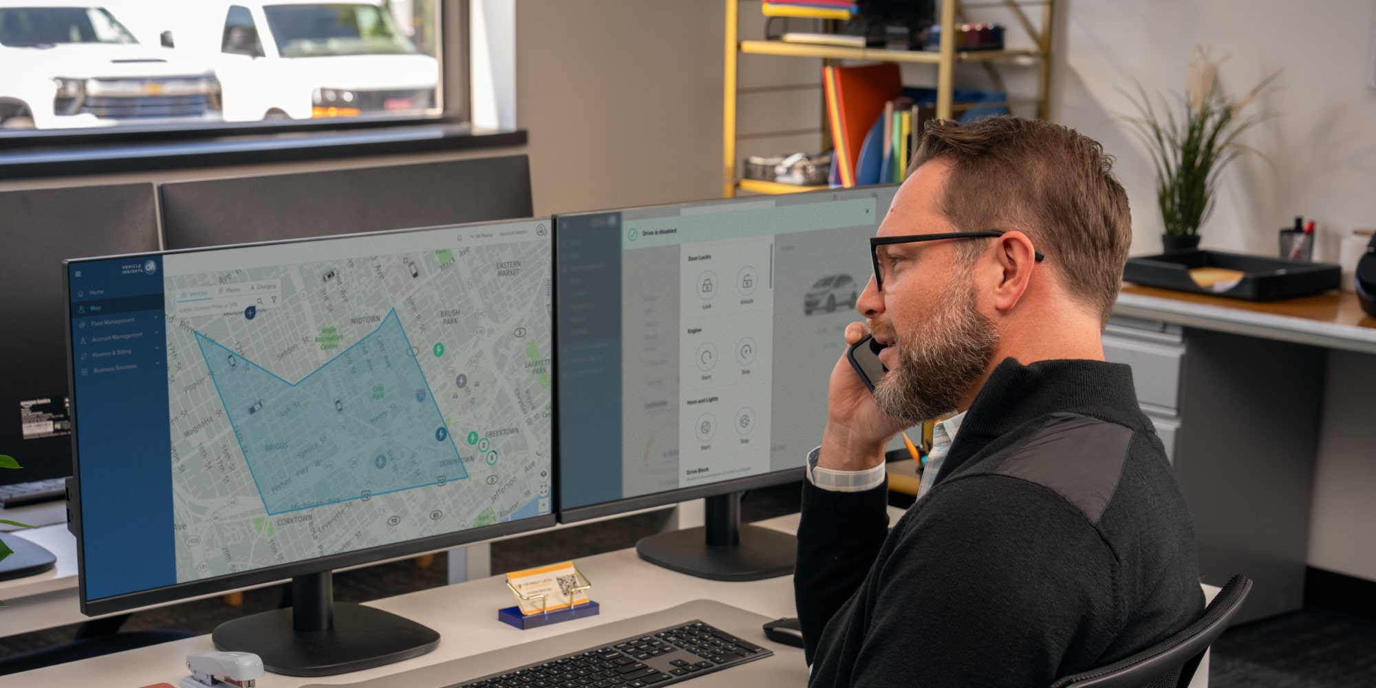 An office worker talking on the phone with telematics on his laptop screen. 
